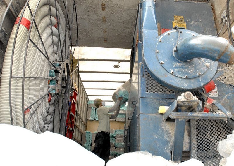 Sophim Kadek of Warm Tech Solutions feeds insulation into a blower machine that pumped the material to the crawl space of a house in Richmond. Federal stimulus money helped create strong demand for energy improvements.
