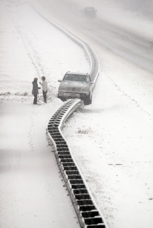 Motorists call for help on a cell phone after climbing out of a vehicle that ended up on a guard rail in the median of Interstate 295 in Cumberland today.