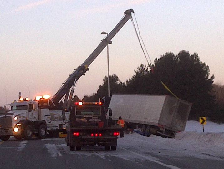 A tow truck pulls a truck from a snowbank at exit 28 southbound in Brunswick on I-295 today. The trucker said he was distracted by the moon Saturday night and went off the highway.