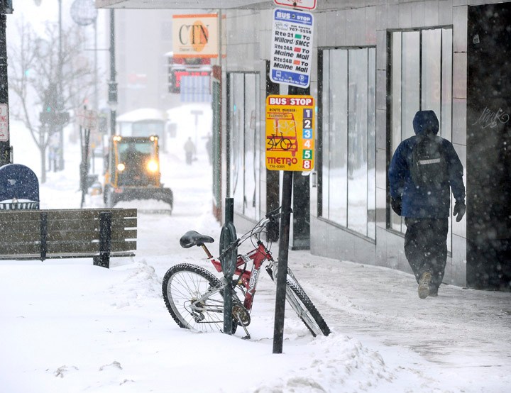 A sidewalk snowplow tries to keep up with the snow accumulating this morning along Congress Street.