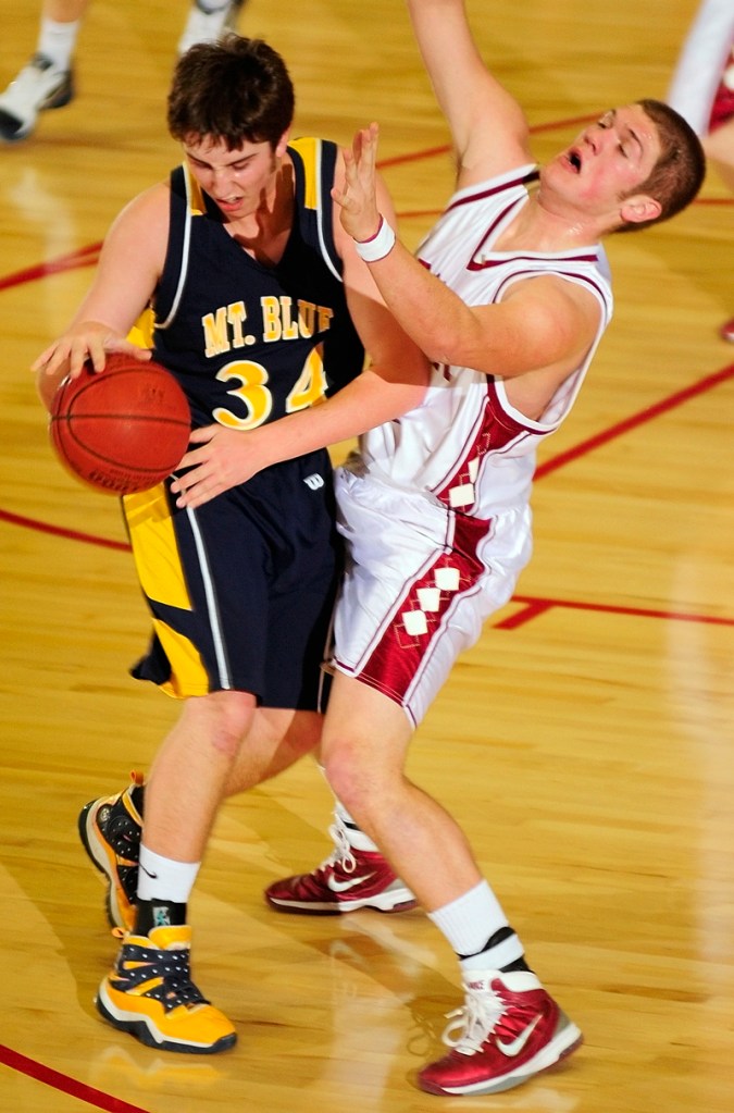 Bangor senior forward Josiah Hartley rocks back after colliding with Mt. Blue senior forward Adam Wiles-Rosell.