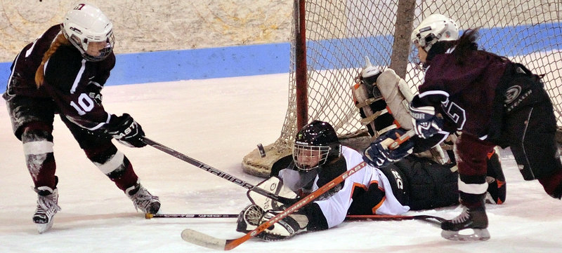 Winslow goalie Jessica Cain keeps her eyes on the puck Friday night while attempting to control a shot by Monica Howland, left, of Greely in the second period. Greely won, 3-2.