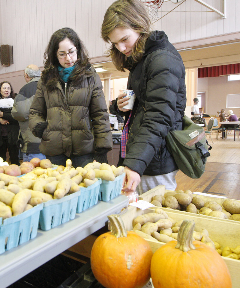 Reva Eiferman, left, and Emily Thielmann check out produce from Buxton’s Snell Family Farm during a CSA fair in Portland.