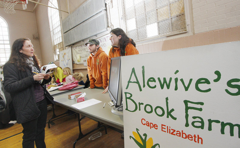 Jessie Grearson of Falmouth talks to Lincoln Jordan and his sister Caitlin Jordan of Alewive’s Brook Farm in Cape Elizabeth during a community-supported agriculture fair Sunday at Woodfords Church. Alewive’s Brook also allows CSA members to use their credits to buy lobsters.