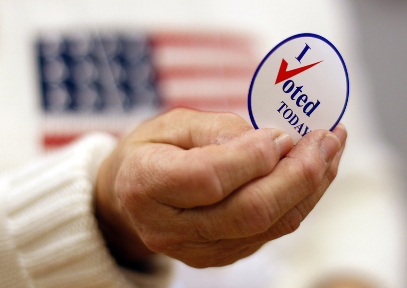 A sticker is handed to a Waterville voter on Election Day, Nov. 2, 2010. Legislation that would require voters to produce a photo ID before casting a ballot is being considered.