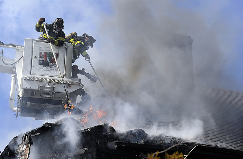 Portland firefighters work to extinguish flames on the roof of a three-story apartment building on Walton Street in Portland on Tuesday.