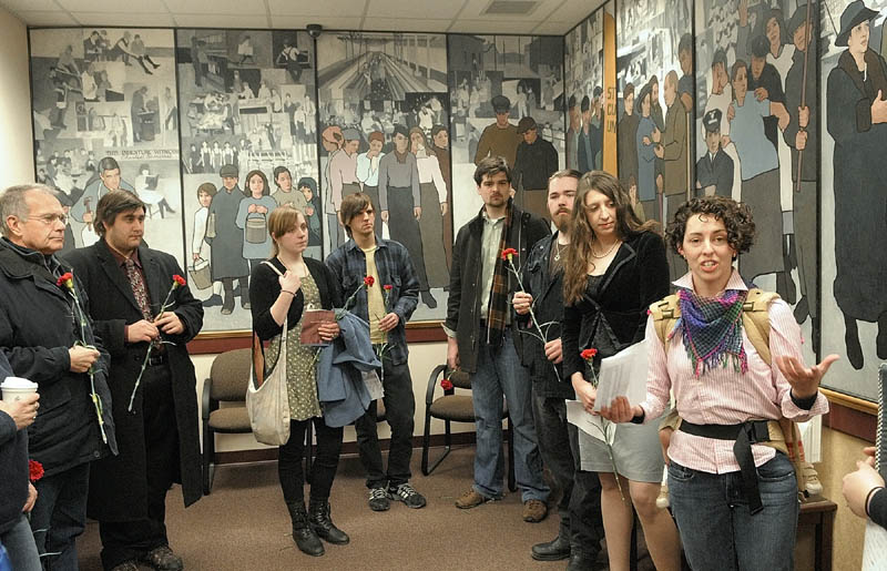 Jessica Graham, of Waterville, right, leads a memorial prayer on the 100th anniversary of the New York Triangle Shirtwaist Factory fire, which killed 146 people as part of an event this morning in front of a mural in the Dept. of Labor lobby in Augusta. This was the first of two events to protest Gov. Paul LePage's order to remove the 36-foot, 11-panel mural Judy Taylor, of Tremont, that was installed there in 2008. There is another scheduled there for noon.