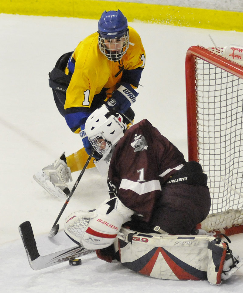 Cameron Bell of Falmouth digs at the puck, trying to jostle it free before goalie Alex Wiggin of Noble is able to cover it up. Falmouth will take a 10-6-3 record to the semifinals. Noble finished with a 13-6 record.