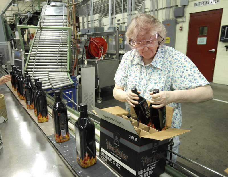 Anita Desrosiers loads bottles of Fire Water, a cinnamon-flavored schnapps, at White Rock Distilleries in Lewiston.