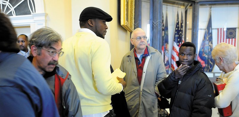 People wait Monday in the Hall of Flags at the State House for a chance to address the Appropriations Committee at a budget hearing. An estimated 100 people rallied in the hall outside of the governor's office before lining up to testify.