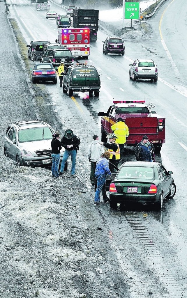 Augusta firefighters and paramedics and a State Police trooper work with people involved in accidents caused by an unusually large pothole in the southbound lane of Interstate 95 near exit 109B on Friday afternoon in Augusta. Staff photo by Joe Phelan Augusta firefighter/paramedics and a State Police trooper work with people involved in accidents in the south bound lane of Interstate 95 near exit 109 B on Friday afternoon in Augusta.