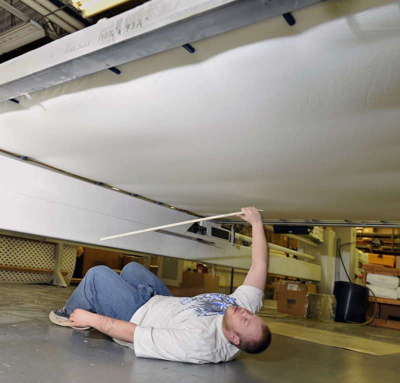 Nicholas Richard slides under a comforter quilting machine and uses a batonlike device to make sure the down is distributed evenly before the fine stitching is completed.