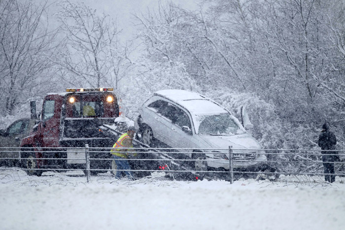 A motorist watches her car hauled onto a flatbed truck after she went off the highway on Interstate 295 in Freeport this morning.