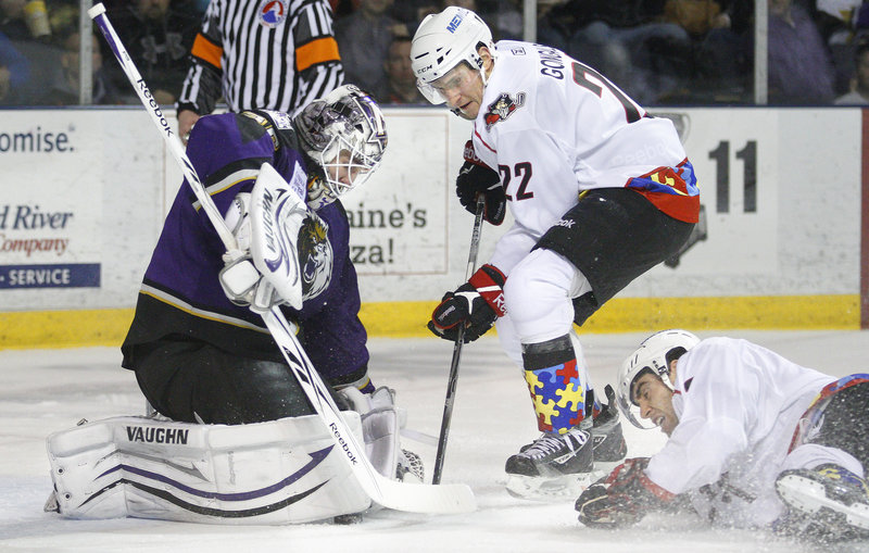 Manchester goalie Jeff Zatkoff traps the puck under his pad as Portland's Igor Gongalsky looks for a rebound in front of sliding teammate Jeff Dimmen.