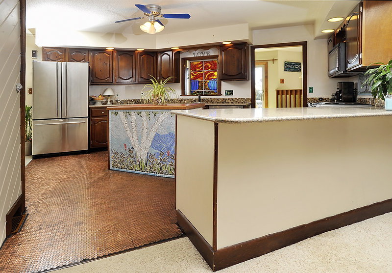 Mosaic artist Amanda Edwards used pennies to create a one-of-a-kind floor for the kitchen of her Falmouth home. The space also includes a mosaic of cut stained glass over her kitchen counter, a colored tile mosaic on the island, and a backsplash covered with pebbles, sea glass and shells her children have collected.