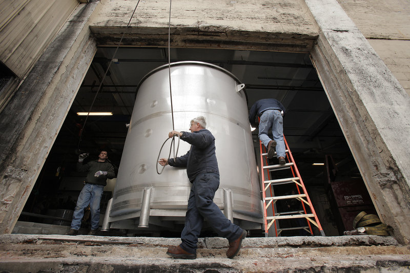 Crane operator Nate Gammon rigs a cable around a new fermentation tank delivered Thursday to Shipyard Brewing in Portland, part of an expansion designed to help the company keep up with orders as summer approaches.