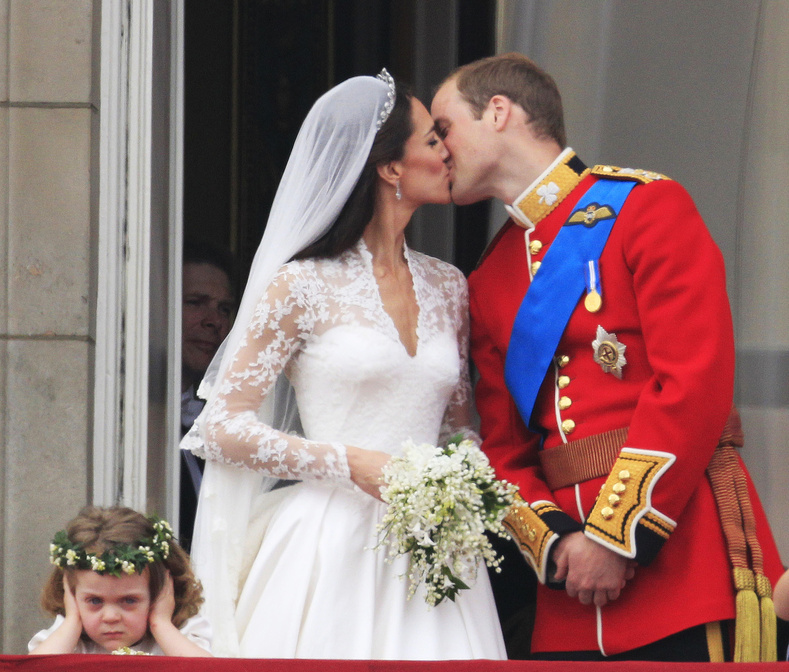 Bridesmaid Grace van Cutsem, left, covers her ears as Britain's Prince William kisses his wife Kate, Duchess of Cambridge, on the balcony of Buckingham Palace after the wedding Friday.