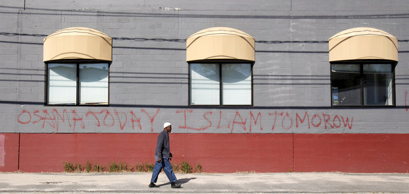 Jirde Mohamed walks past graffiti Monday on the Maine Muslims Community Center on Anderson Street in Portland. The writing reads: "Osama today Islam tomorow (sic)." Another writing read: "Long live the West."