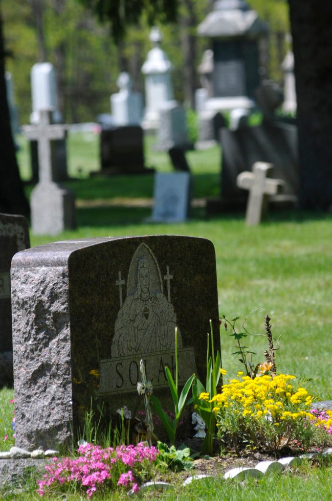 Lilies, tulips and other varieties of flowers grace the front of headstones at Calvary Cemetery in South Portland. Every cemetery has different rules about what can be done with a grave site – some allow permanent plantings, some allow plastic flowers, and some don’t allow anything. At Calvary, for example, plants or planters are allowed only in front of monuments. It’s best to check on the rules of a particular burying ground before you plant something or place a container at a grave site.