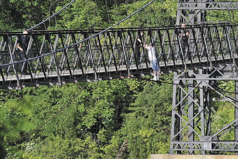 TALKING IT THROUGH: Winslow police officer Linda Smedberg, center, reaches out to shake hands with a man threatening to jump from the Two Cent Bridge over the Kennebec River Sunday evening. After a half-hour of talking with Smedberg, the man was convinced to climb back over and was taken to the hospital for an evaluation.