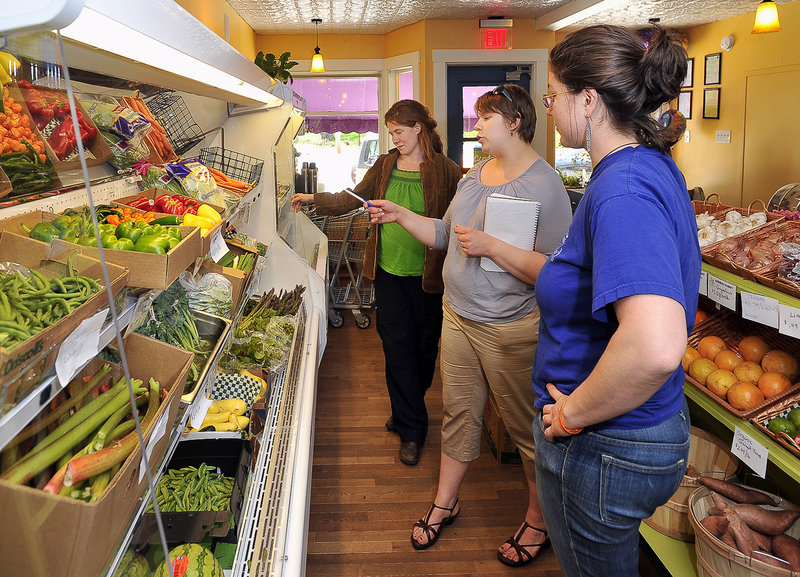 Marada, left, and Leah Cook, right, who are launching a company to process Maine-grown organic vegetables, talk to Kate Bathras, center, manager of Bathras Market in South Portland, about products from their organic food delivery service.