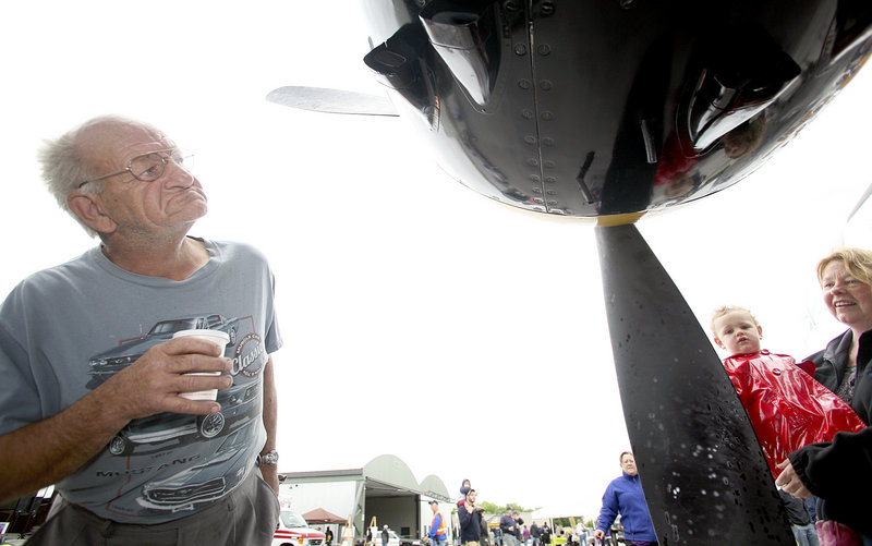 Wayne Young of South Portland inspects a North American RB-25 Mitchell Bomber as Beth Lunt of Old Orchard Beach holds Ivy Diou, 1, of Portland so she can touch a propeller.