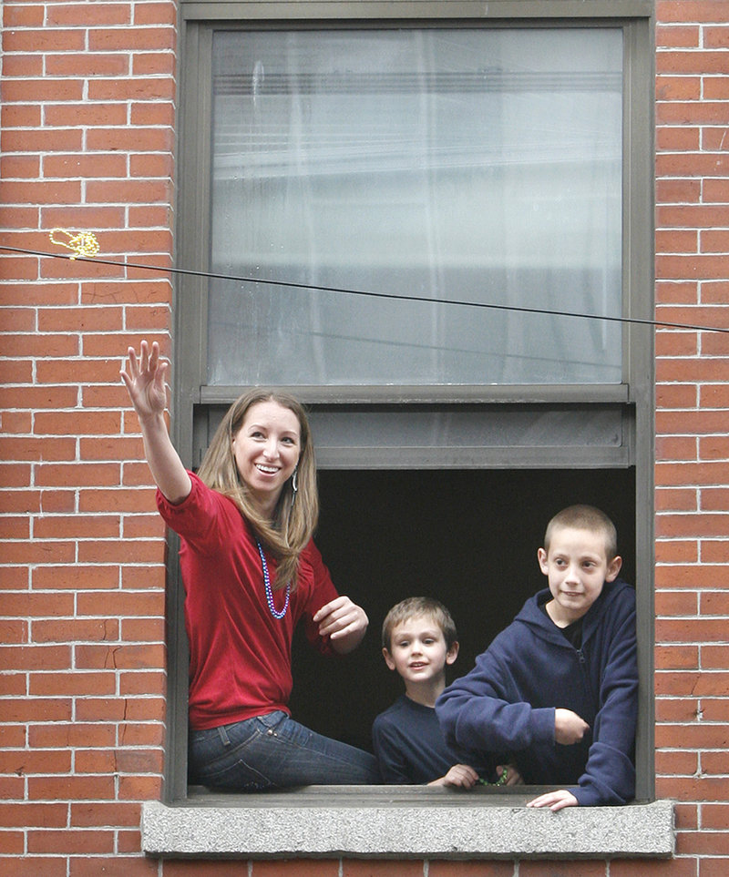 Jennifer Eagan throws beads from her apartment down to people on Exchange Street with the help of Drew Gannon, middle, and his brother Travis.