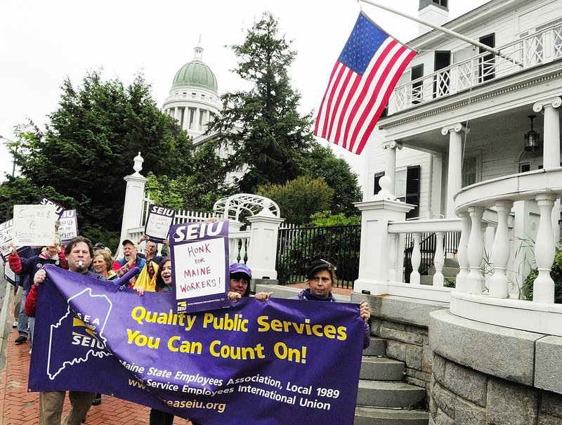 Protesters march past the Blaine House after speeches Saturday in Augusta. Many of the speakers said the governor shouldn’t have hired a New York negotiator at $295 an hour.
