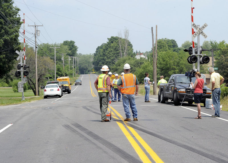 Officials with the Maine Department of Transportation and Springfield Terminal Railway, the track’s owner, inspect the site of Monday’s fatal collision Tuesday. Skid marks that stretch more than 200 feet may provide clues to how fast the truck was going.