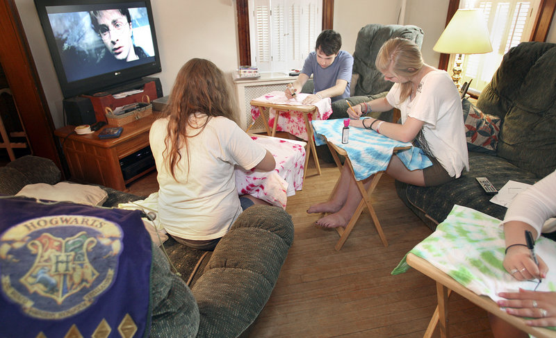 With “Harry Potter and the Prisoner of Azkaban” on the television, Molly Ekholm, left, Connor Igo, middle, and Siobhan Baker make Quidditch jerseys at Igo’s home in South Portland. They’ll wear the shirts when they go see the final Harry Potter movie being shown at 12:01 a.m. Friday.