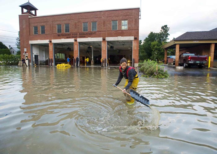 Firefighter Mandy Drake clears a storm drain today in front of the fire department in Waterbury, Vt., in the wake of tropical storm Irene. The building was evacuated as high water from the Winooski River flooded downtown Sunday. Almost 50,000 Vermont utility customers were without power today, hundreds of roads were closed and a number of bridges destroyed by the "epic" flooding caused by by the remnants of Irene.