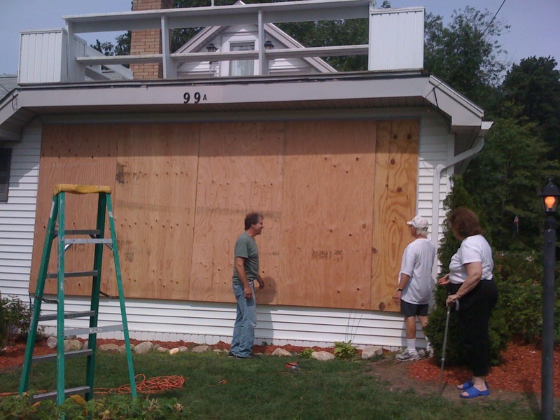 John and Clare Gambino, right, look at the work of Cape Elizabeth builder Larry Skillings as he puts up plywood panels to protect the large front picture window on their home on East Grand Ave. in Scarborough. It's the first time in the 32 years they've lived there that they have put up protection from any storm, according to the Gambinos.