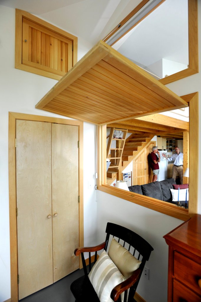 A wooden door drops down to close a pass-through between the bedroom and the living area.