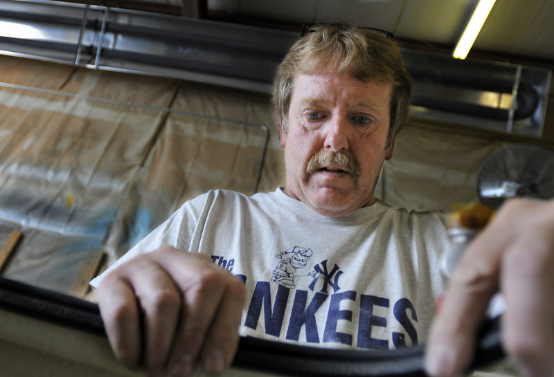 Glenn Smith, a carpenter at Lyman-Morse, fits a gasket around one of the company’s solar-powered cubes.