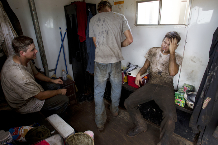 Austin Mitchell, right, takes a break with Ben Shaw, left, and Ryan Letho, center, while working an oil derrick outside of Williston, N.D.