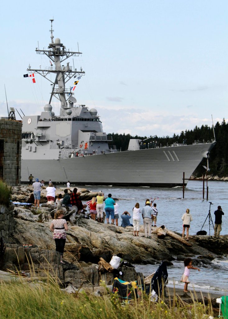 Spectators stand on the bank of the Kennebec River on Thursday as the Spruance passes.