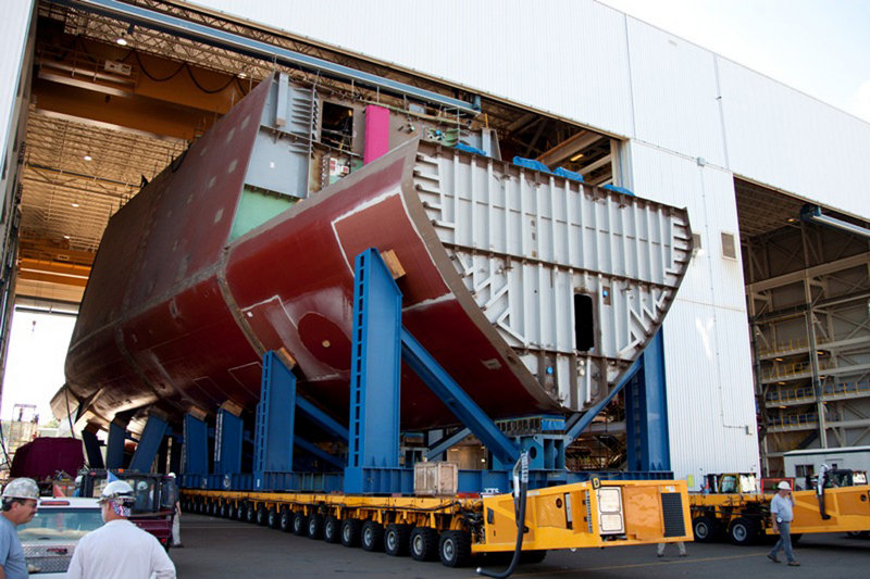 Shipyard workers guide a hull section of a Zumwalt-class guided missile destroyer being built at the shipyard. It is the first of the new class of ship, and Bath Iron Works has been chosen to work on two more.