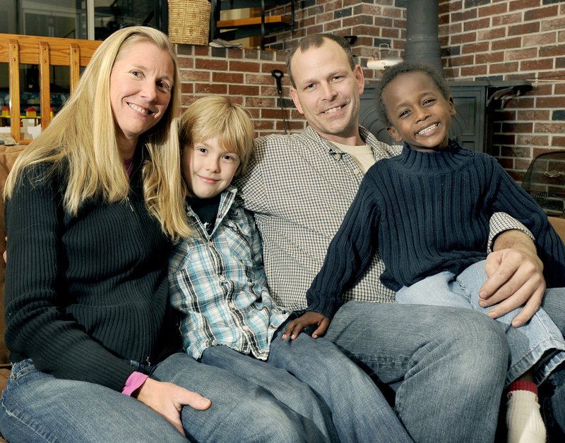 Laura deDoes and her husband, Patrick Mendelsohn, pose with their two children, Dane, 8, and Bezabeh, 4, at their home in Cumberland.