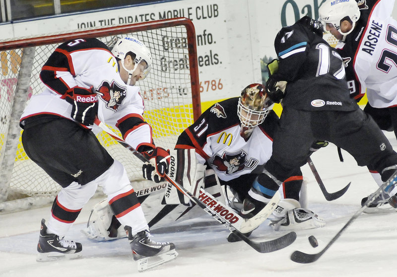 Portland goalie Curtis McElhinney keeps his eye on the puck Friday night as it bounces in front of the net and Tommy Wingels of the Worcester Sharks tries to put it in. Chris Summers, left, and Dean Arsene help on defense.