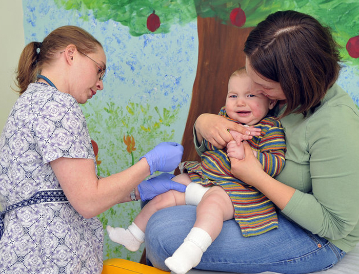 Medical assistant Shannon La Belle administers a shot to 7-month-old Nathaniel as he is held last week by his mother, Christine Kelly of Cumberland. Following a national trend, the decline in Maine’s immunization rate poses risks to children and others, medical experts say.