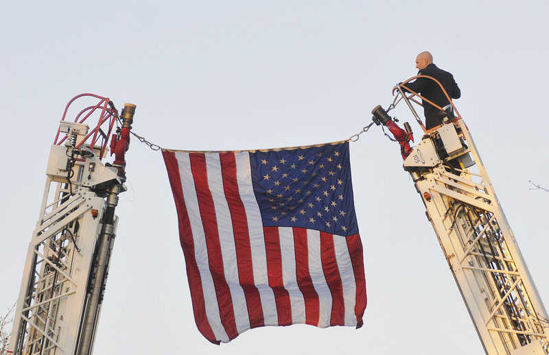 James Westburg of the Portland Fire Department hangs a flag across Ocean Avenue in preparation for the 10 truckfuls of wreaths and the groups accompanying them.