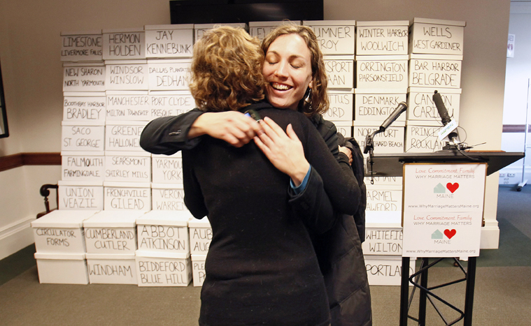 Ali Vanderzanden, political director for EqualityMaine, hugs a friend Thursday at the State House in Augusta. The boxes contain more than 105,000 signatures collected by supporters of gay marriage who are hoping to force a second referendum on the issue.