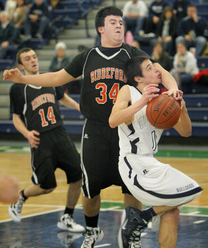 Nathan McKeown of Biddeford prevents Portland’s Justin Zukowski from taking a shot Tuesday night at the Portland Expo. Zukowski scored 14 points to pace the Bulldogs to a 61-52 win.