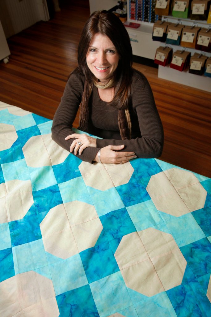 Kathie Ferland-Medina, owner of Kathie’s Quilt Shoppe in Sanford, with one of her designs, “Paradise Beach.” Her shop was chosen from hundreds of applicants for a national magazine feature.