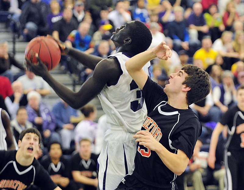Thiwat Thiwat of Deering drives to the basket Friday night against Matt Cote of Biddeford during the first half of their Western Class A quarterfinal at the Portland Expo. Cote knocked the ball away on the play. Deering pulled away for a 66-54 victory.