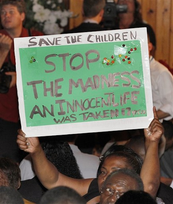 A group gathers and chants "we want justice", on Tuesday, March. 20, 2012, in Sanford, Fla. in protest against the lack of prosecution in reference to the shooting death of 17 year old Trayvon Martin who was shot and killed by George Zimmerman a neighborhood watchman. (AP Photo/Reinhold Matay)