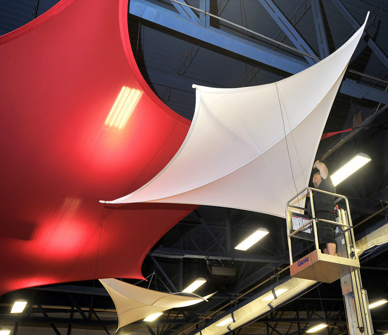 Luigi DiFazio III, an employee of Transformit in Gorham, installs a decorative and sound-absorbing tension fabric structure Thursday in the rafters of the HUB Athletic Center at Southern Maine Community College in South Portland.