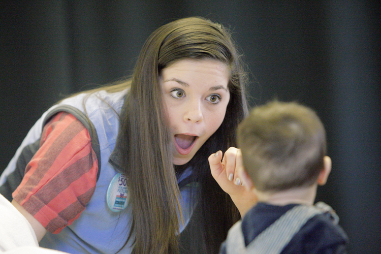 Kaitlyn Page tries to get 7-month-old Henry Bernard to smile during a casting call and photo shoot for the Harold Alfond College Challenge on Saturday. Page was a volunteer at the event, which took place on the University of Southern Maine campus in Portland