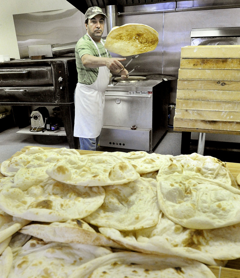 Tandoor owner Audai Naser tosses a hot flatbread from the oven on to a table to cool.