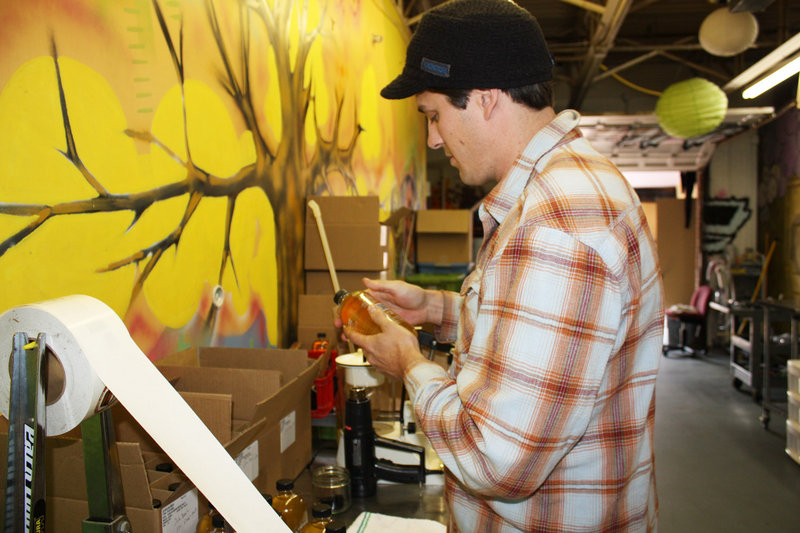 Reid Emmerich attaches a label to a bottle of Urban Farm Fermentory Kombucha Culture at the company’s facility in Portland. The new line, featuring ginger, wild blueberry and oak barrel varieties, hits store shelves this week.